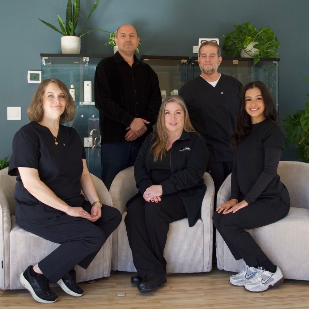 The ZClinic team together in the clinic, seated and standing in front of the product cabinets